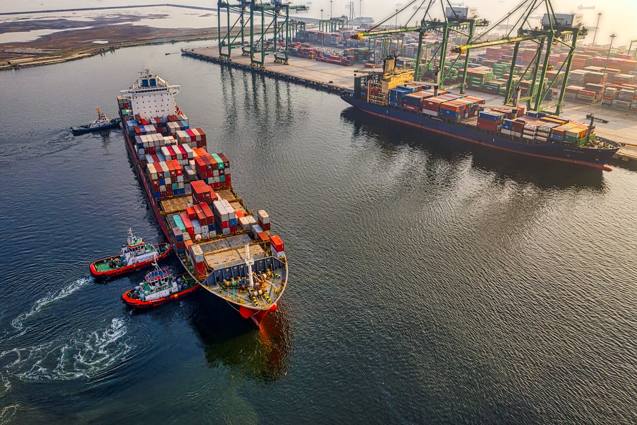 Aerial shot of cargo ships and cranes at North Jakarta port, showcasing global shipping and logistics.